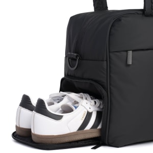 Black bag with a compartment holding white sneakers